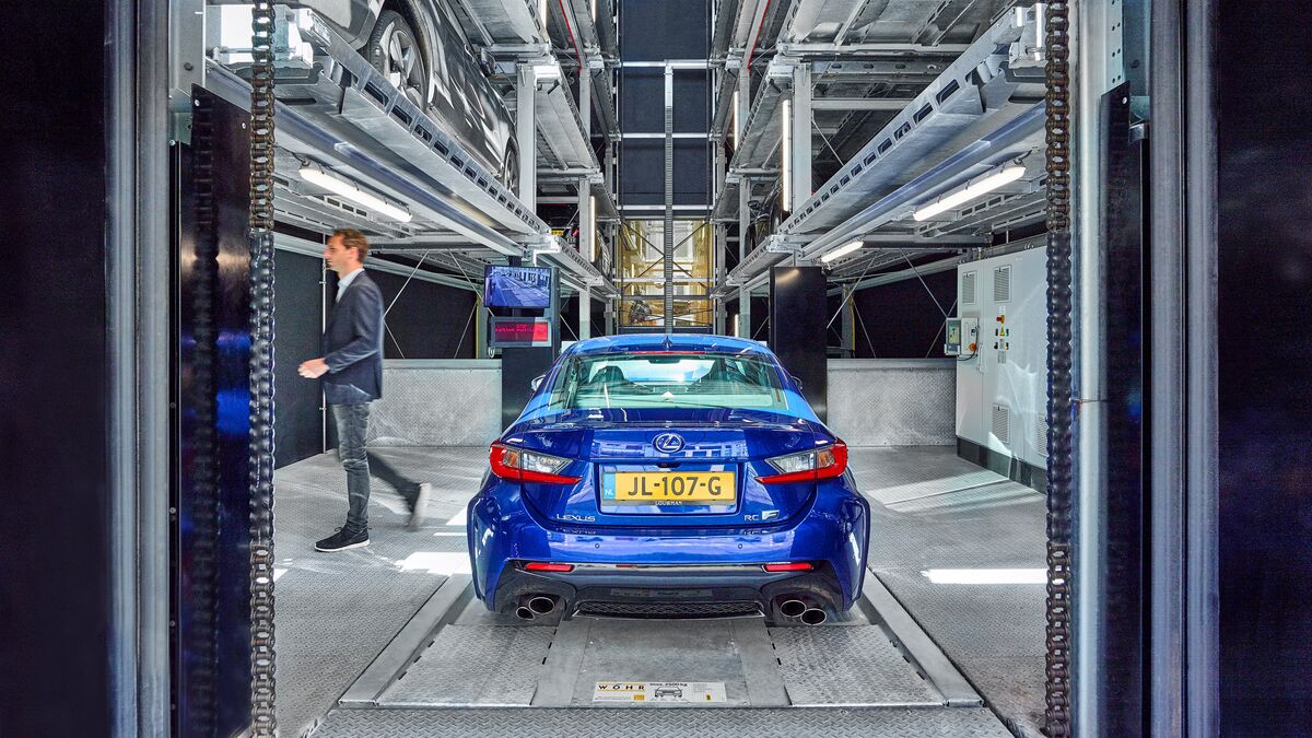 A blue car is parked in the entry bay of a car parking system