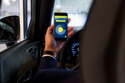 A person holds up their mobile phone with the app open
