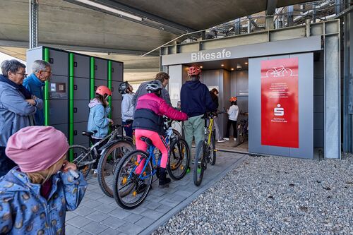 Children on bicycles stand in front of the entrance to the automated bicycle parking system