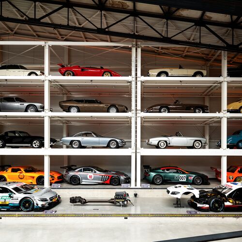A wall-mounted shelf full of cars in a museum