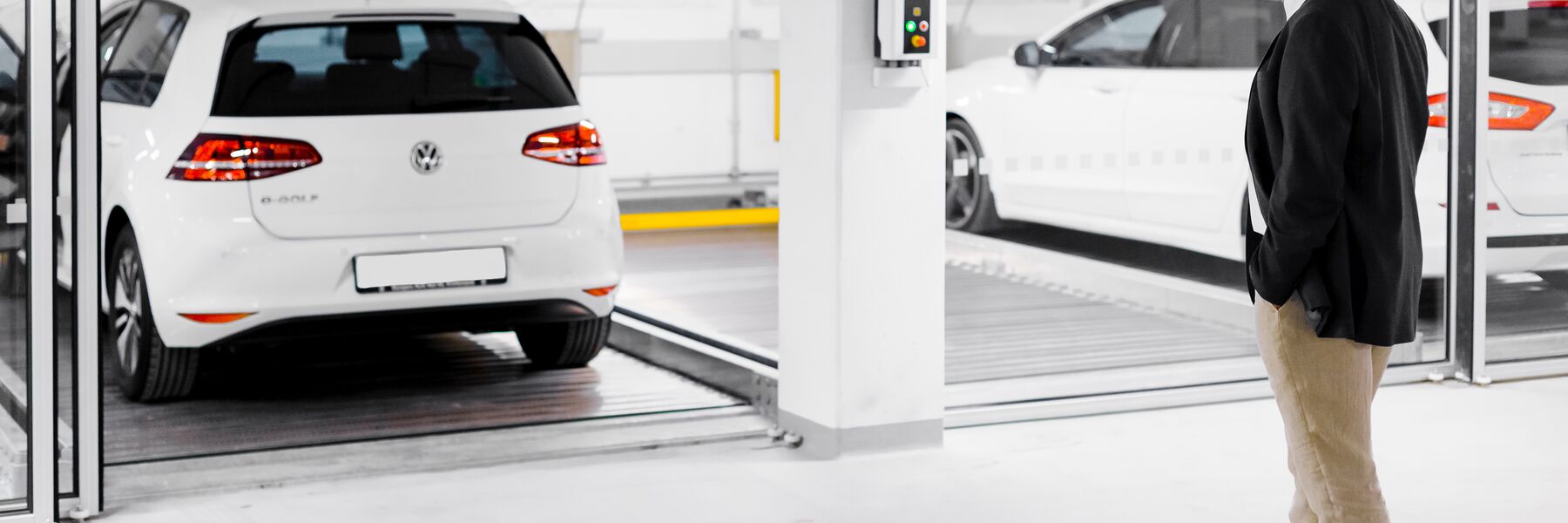 A man stands in front of a parking system with cars