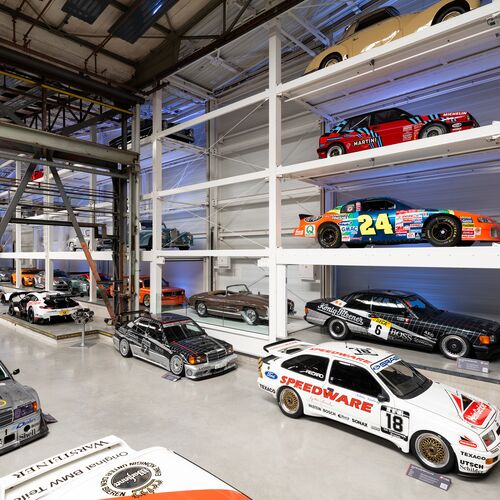 A wall-mounted shelf full of cars in a museum