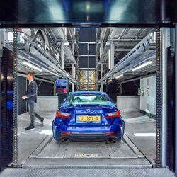 A blue car is parked in the entry bay of a car parking system