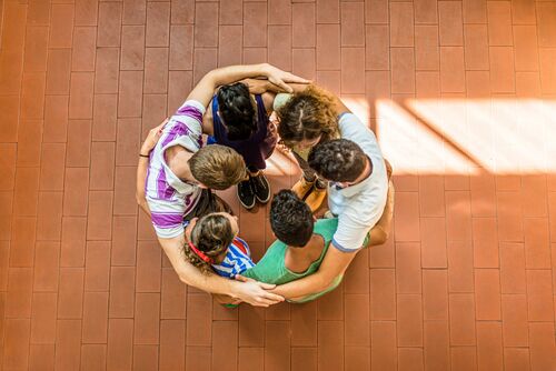 People stand in a circle and embrace one another