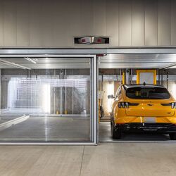 The image shows several vehicles in glazed parking spaces of a parking system in a modern underground garage.
