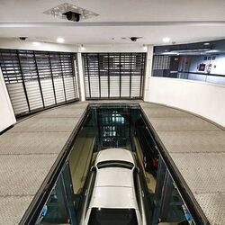 The car is positioned in a drive-in bay on a parking platform and moves downwards