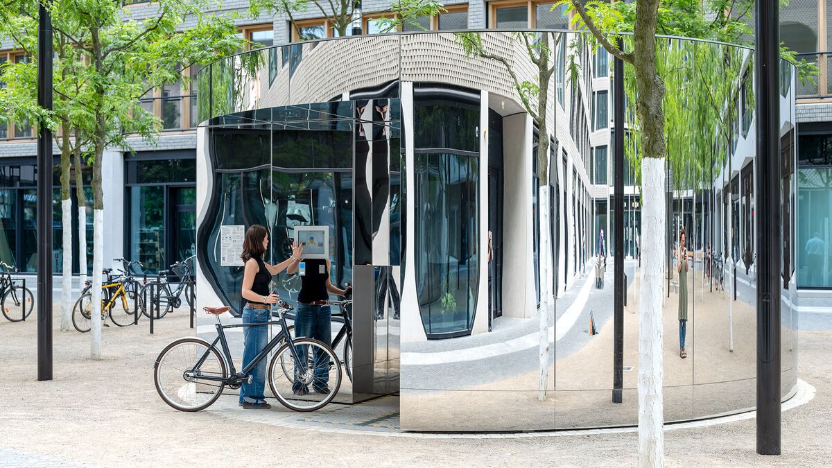 A woman with a bicycle operates a monitor at the bicycle parking system
