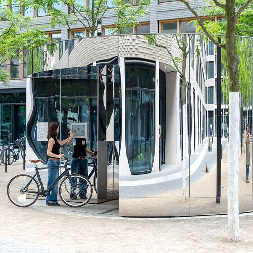 A woman with a bicycle operates a monitor at the bicycle parking system