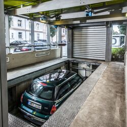 The car is positioned on a parking platform in an entry bay and is lowered