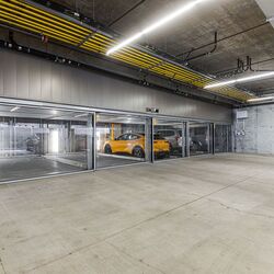 The image shows a modern underground garage with several glazed parking spaces of a parking system.