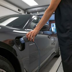 A woman plugs an electric charging cable into her car