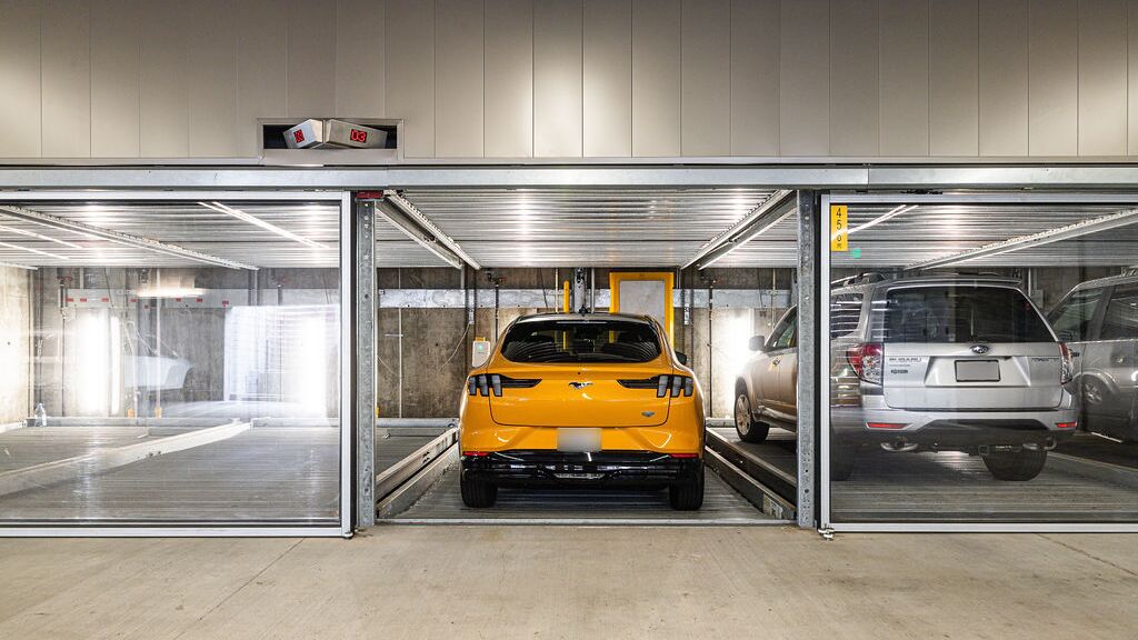 The image shows a modern underground garage with several glazed parking spaces of a parking system.