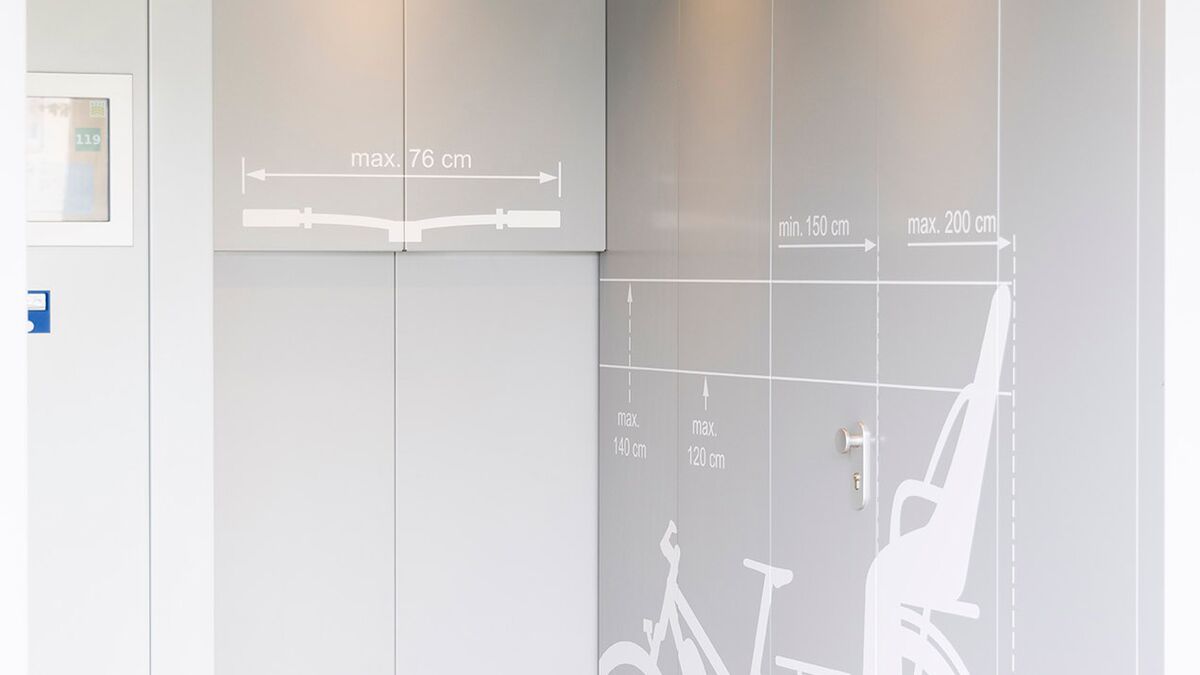 Entrance area of a bicycle parking tower with a bicycle pictogram on the wall