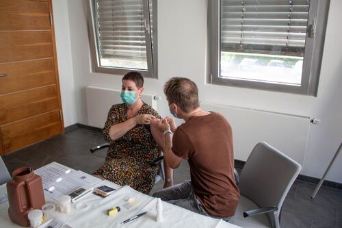 Photo of a doctor administering the vaccine to a member of staff