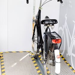 Bicycle on a guide rail in front of an automatic bicycle parking system