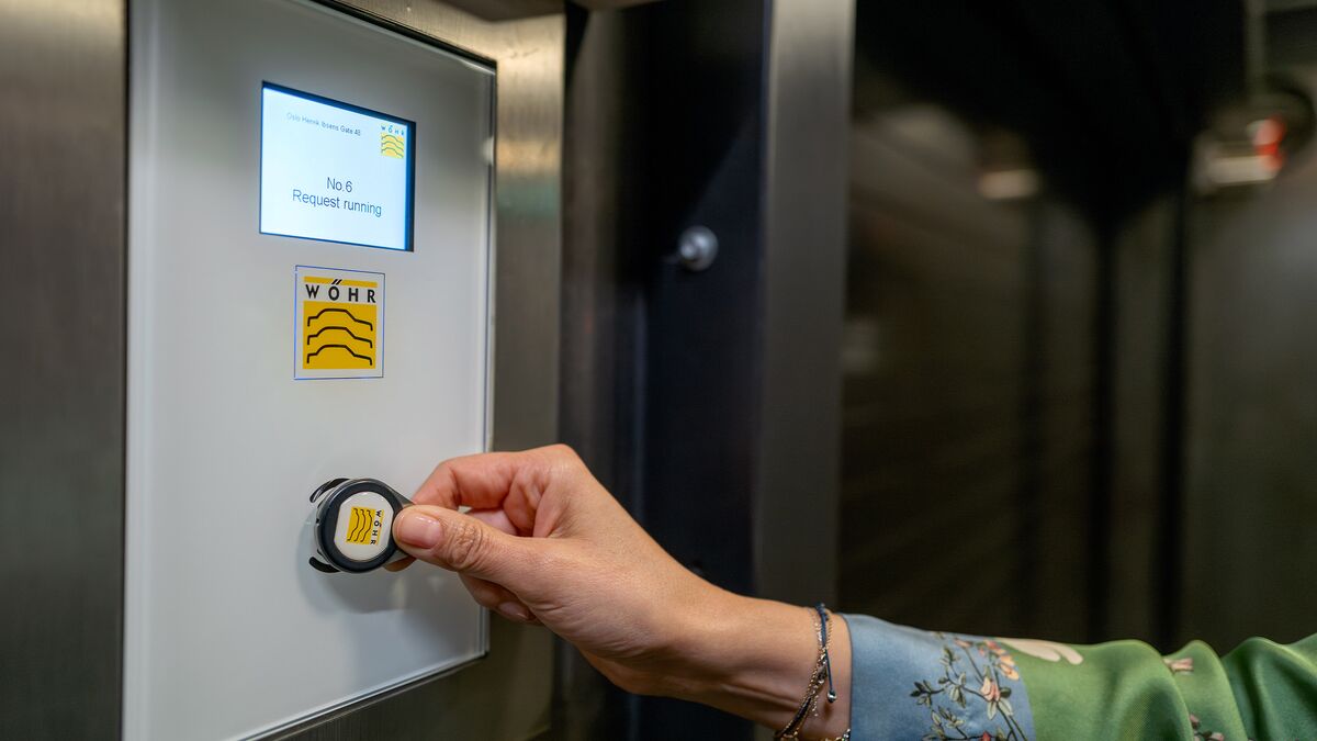 A woman holds an RFID chip up to the sensor on a control panel