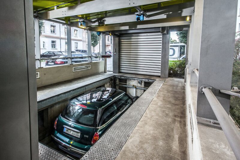 The car is positioned on a parking platform in an entry bay and is lowered