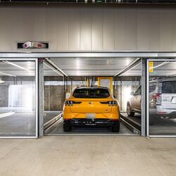 The image shows a modern underground garage with several glazed parking spaces of a parking system.
