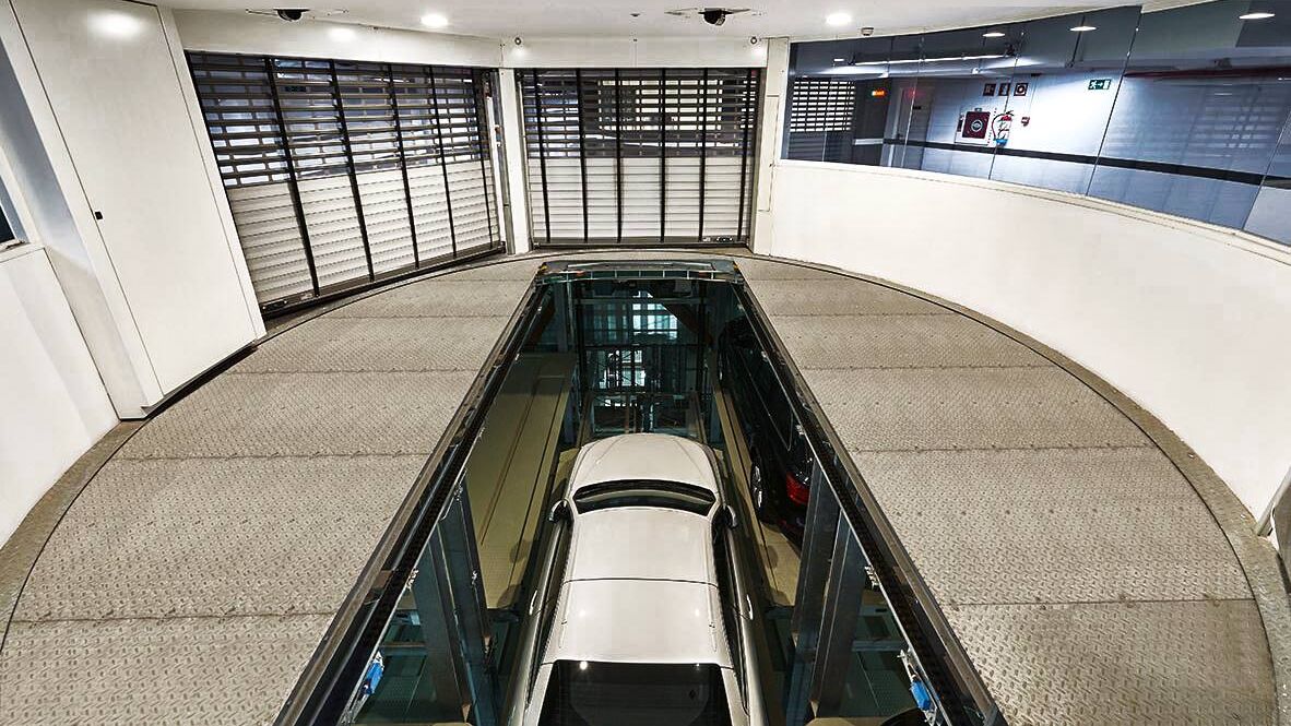 The car is positioned in a drive-in bay on a parking platform and moves downwards