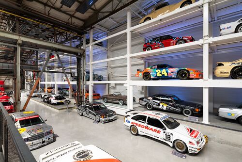 A wall-mounted shelf full of cars in a museum