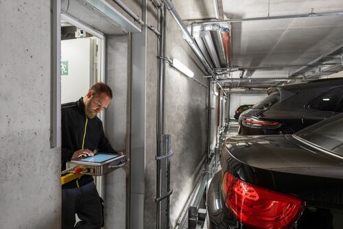 A service technician repairs a parking system