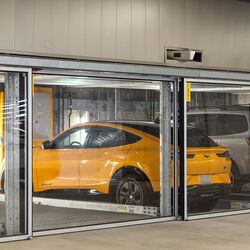 The image shows several vehicles in glazed parking spaces of a parking system in a modern underground garage.