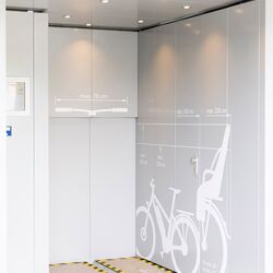Entrance area of a bicycle parking tower with a bicycle pictogram on the wall