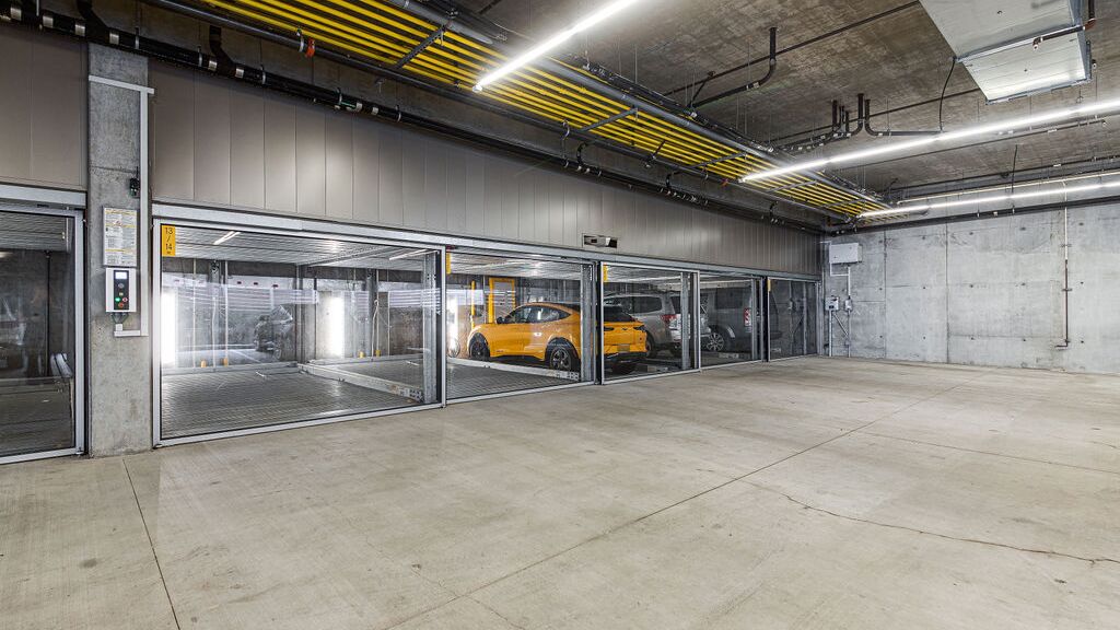 The image shows a modern underground garage with several glazed parking spaces of a parking system.